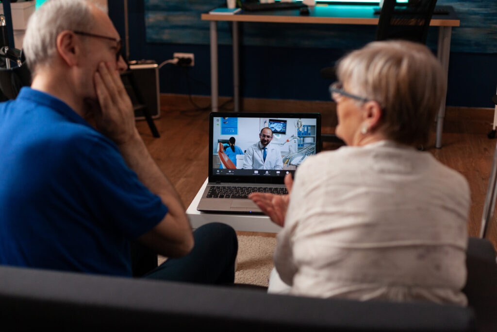 couple talking on video call with dentist using laptop at home